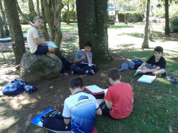 Alunos se reúnem ao ar livre para fazer as tarefas escolares